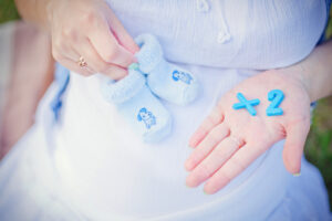 pregnant belly with hands showing baby shoes and x2