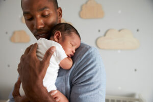 dad holding newborn baby in nursery