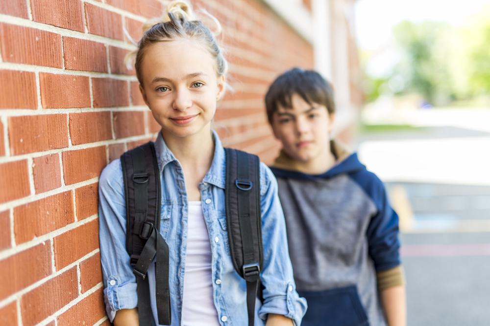 boy and girl in front of brick wall